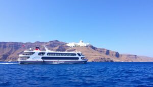 Ferry approaching Santorini with the iconic white buildings visible on the caldera cliffs - Santorini Greece Travel Guide